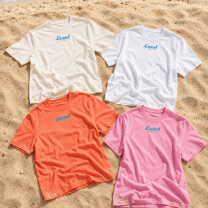 4 Lund shirts gesammelt Vier Lund-Shirts – Blaues Logo in Creme, Weiß, Orange und Rosa, jeweils mit einem auffälligen blauen Logo, das auf dem Sand in Strandnähe zu sehen ist.