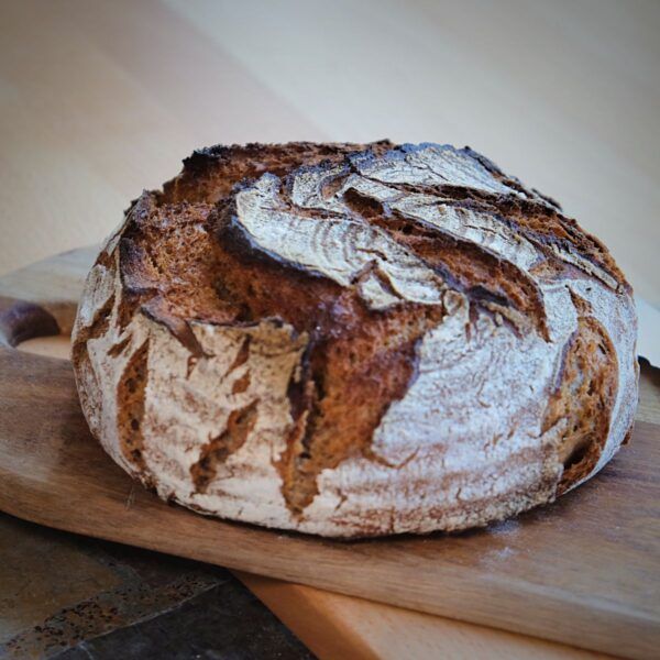Bio_Steinofenbrot_SylterBrot Ein Laib BIO STEINOFENBROT auf einem Holzbrett.