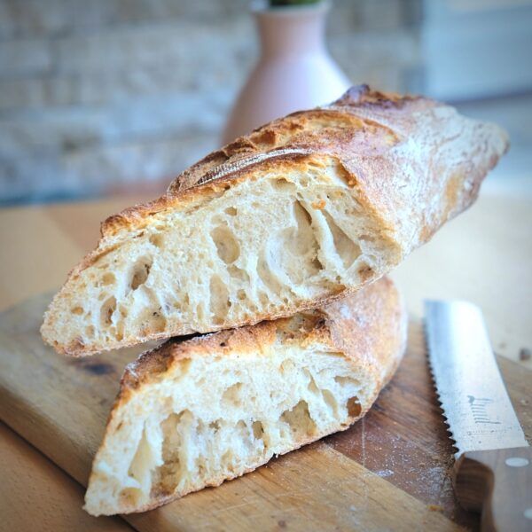 Dinkel_baguette_Lund_Sylt-2 Zwei Scheiben L'oven Fresh Multi-Samenbrot auf einem Schneidebrett.