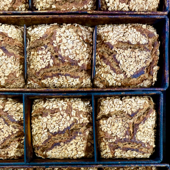 BIO DINKEL-VOLLKORN 800g Brote, mit Hafer belegt, hergestellt aus Mehrkorn-BIO-Zutaten, angerichtet im Backblech.
