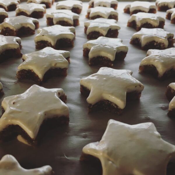 Lund-Sylt-Zimt-see-Sterne-sylter-zimtsterne-scaled Sternförmige Kekse mit Zuckerguss und „KANEEL“ ZIMT-STERNE auf einem Backblech.