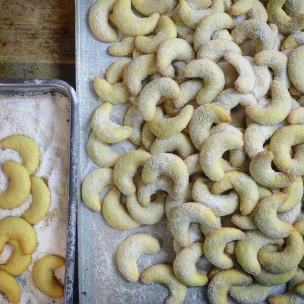 Lund-sylt-vanille-Kipfel-Vanillekipferl-rezept-suedspitze Ein Tablett mit TAHITI-VANILLE KIPFEL mit Puderzucker darauf.