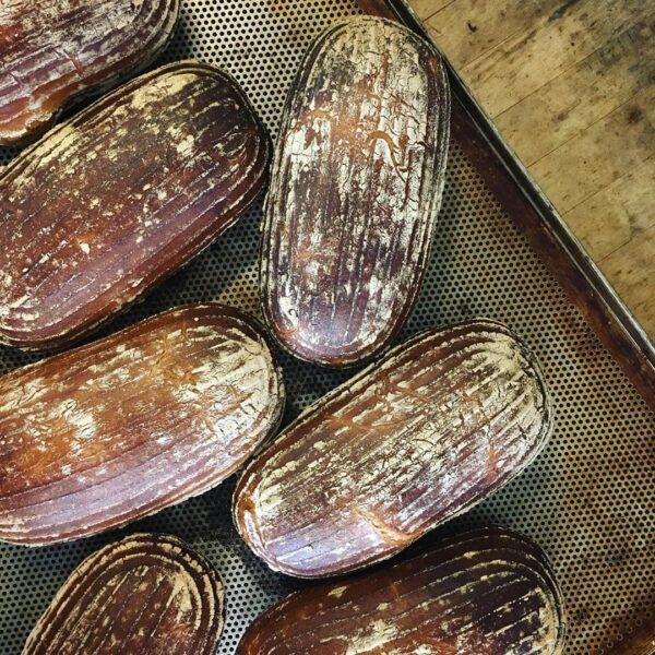 Roggenmischbrot_Wittenberger_Sylt_Bio_Brot_steinofen_rustikal_sourdough Auf einem Holztisch steht ein Tablett mit BIO MISCHBROT 500g.