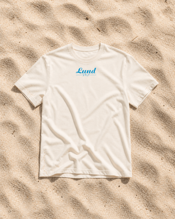 Shirt naturalraw auf sand blaues logo Mock up Ein weißes „LundSylt“-T-Shirt in Größe XXL mit auffälliger blauer Aufschrift liegt im strahlenden Sonnenlicht auf strukturiertem Sand.