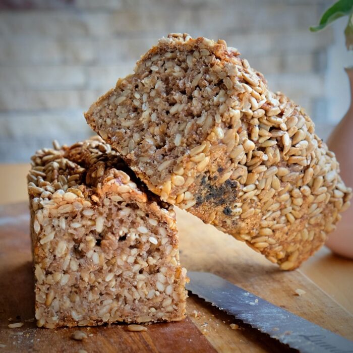 Sonnenblumenkern-Stange-Friesen-Voillkornbrot-Lund-Sylt-Sauerteig-1 Ein BIO SONNEN-BLUMEN-STANGE Laib Brot mit Sesam auf einem Schneidebrett.
