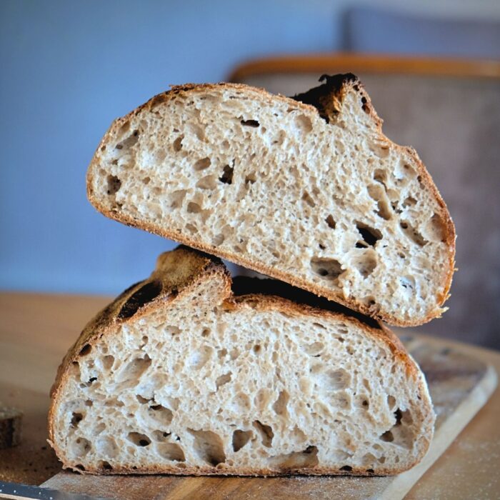 Sylter-Sauerteigbrot-Lund-Sylt-Produktfoto-Anschnitt Zwei Scheiben Roggensauerteigbrot auf einem Holzbrett.