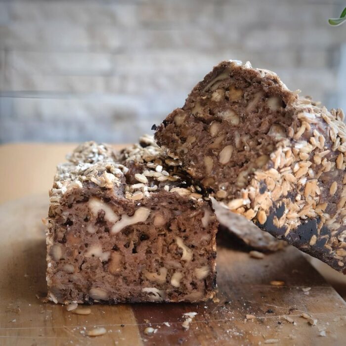 Walnuss-Stange-Friesen-Voillkornbrot-Lund-Sylt-Sauerteig-1 Eine Scheibe MANDELBISCOTTI mit Nüssen und Hafer auf einem Schneidebrett.