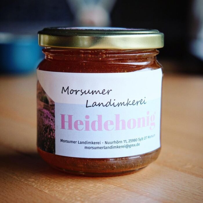 sylter_heide_honig_lund_sylt Ein Glas Sylter Heidehonig steht auf einem Tisch.
